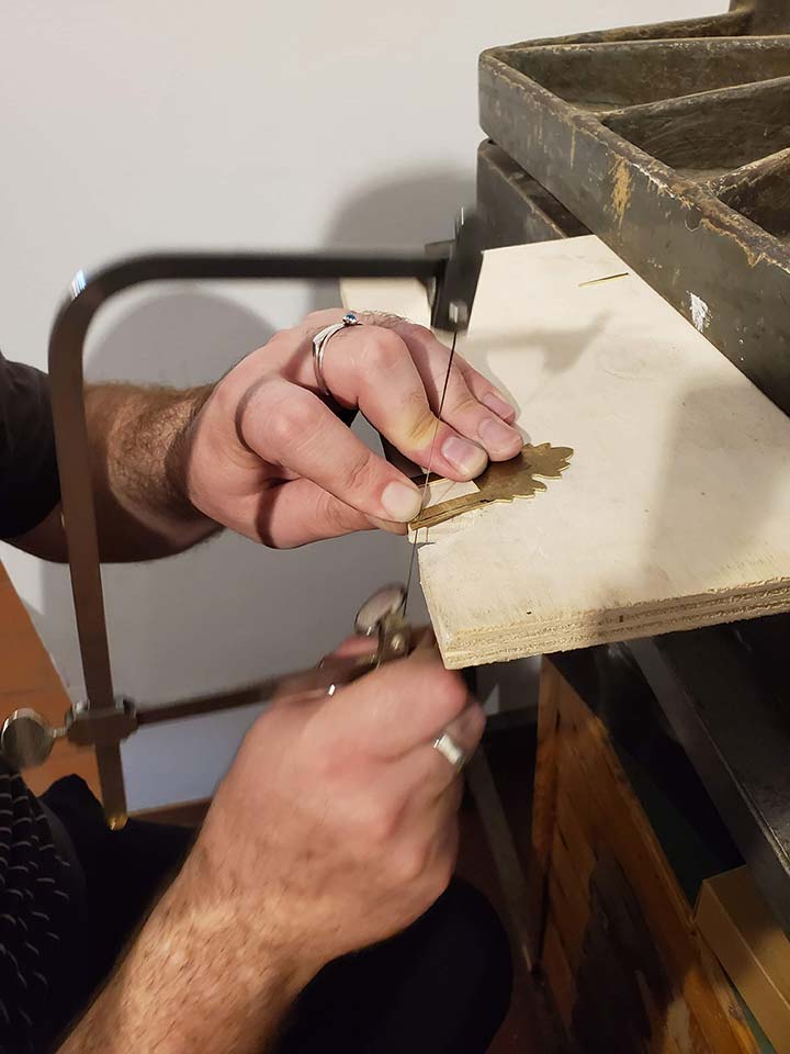 A student practicing sawing metal to make clasps for their facsimilie